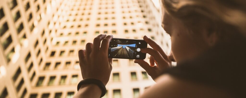 Photo d'une femme qui prend en photo un building avec son iPhone